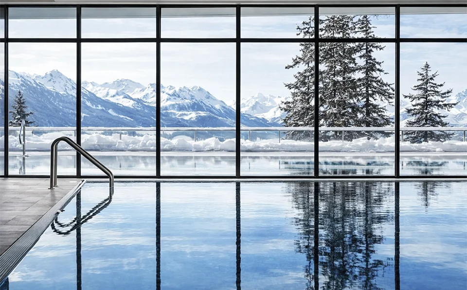 A beautifully tranquil swimming pool with a snowy mountain view out of the floor to ceiling window