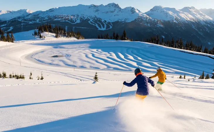 A male and a female skier enjoy their ski holiday in Canada in a vast and inspiring mountain landscape