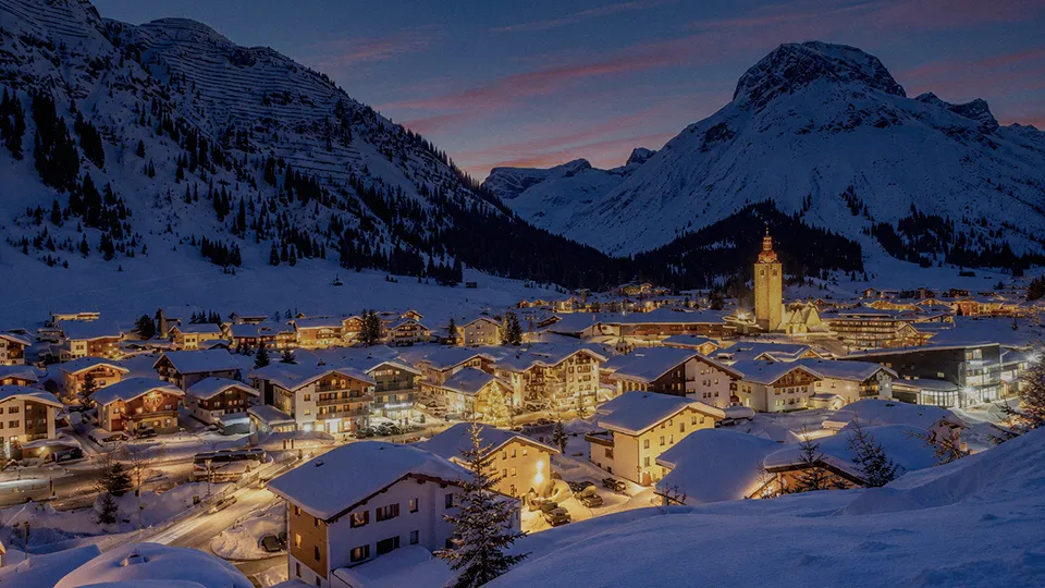 An alpine village at dusk with glowing lights on a Christmas Ski Holiday