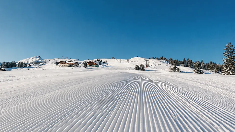 Quiet early December skiing on a wide groomed piste in a high altitude Alpine resort