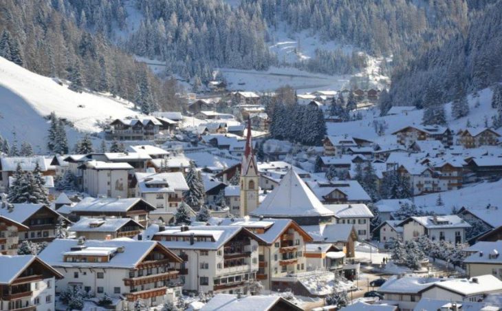 The ski resort of Selva in Italy. The resort is shown from a distance with snowy roofs and a church.